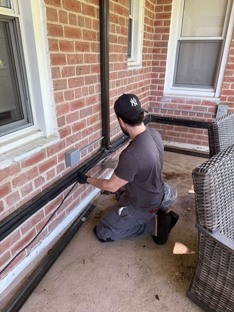 Technician installing air-conditioning lines on a brick porch